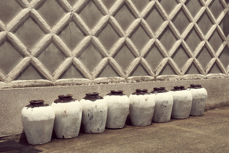 row of traditional Japanese ceramic sake bottles close to the ancient building wallの写真素材