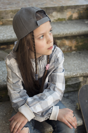urban girl  in peaked gray cap sit on stairsの写真素材