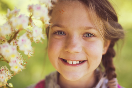 smiling child girl near blooming chestnut treeの写真素材