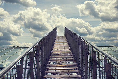 straight metallic stairway leading to the cloudy sky by daytimeの写真素材
