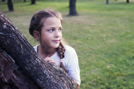 girl behind huge tree in evening garden