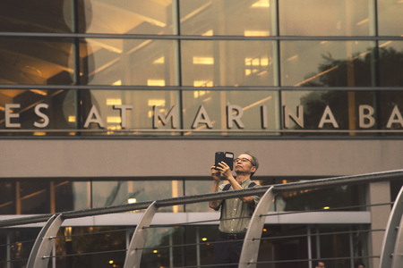 SINGAPORE - NOVEMBER 17: man takes photo on smartphone in modern architectural environment in Singapore, Singapore on November 17, 2014.のeditorial素材
