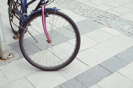 urban pavement background with focus on front wheel of vintage bicycle