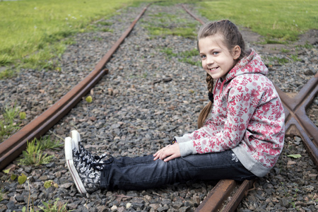 smiling child girl sitting on railsの写真素材
