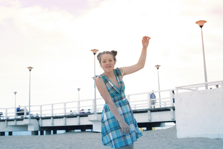 cheerful teenage girl playing near beach pier by eveningの写真素材