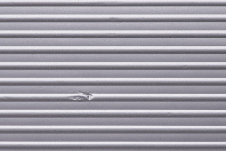 corrugated metallic surface with small dent, horizontal orientationの写真素材