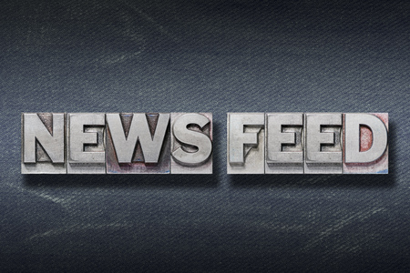 news feed phrase made from metallic letterpress on dark jeans background