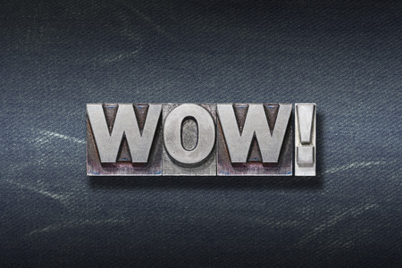 wow word made from metallic letterpress on dark jeans backgroundの写真素材