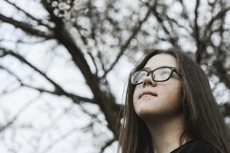daydreaming girl outdoor with blossom tree branches behindの写真素材