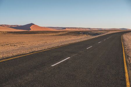 empty highway in Namibia with red dunes asideの写真素材