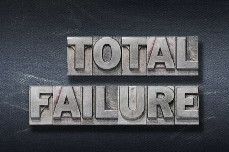 total failure phrase made from metallic letterpress on dark jeans background