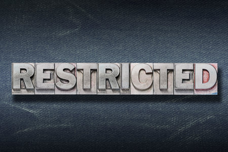 restricted word made from metallic letterpress on dark jeans backgroundの写真素材