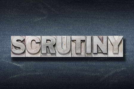 scrutiny word made from metallic letterpress on dark jeans backgroundの写真素材