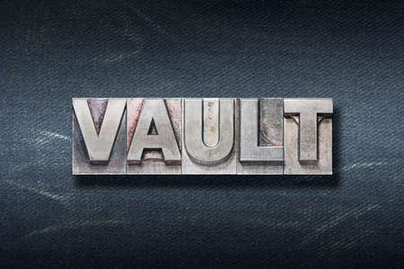 vault word made from metallic letterpress on dark jeans backgroundの写真素材