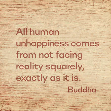All human unhappiness comes from not facing reality squarely, exactly as it is - famous quote of Gautama Buddha printed on grunge wooden boardの写真素材