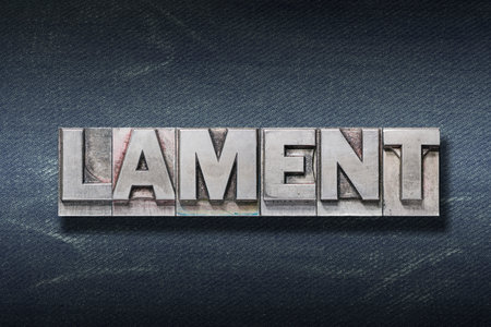 lament word made from metallic letterpress on dark jeans backgroundの写真素材