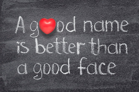 A good name is better than a good face Chinese saying written on chalkboard with red heart symbolの写真素材