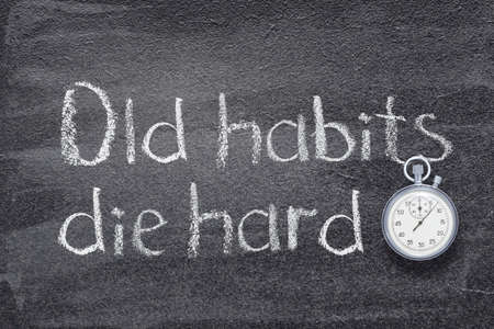 old habits die hard proverb written on chalkboard with vintage precise stopwatchの写真素材