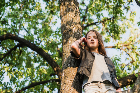 teenage girl taken from below near big tree by summer eveningの写真素材