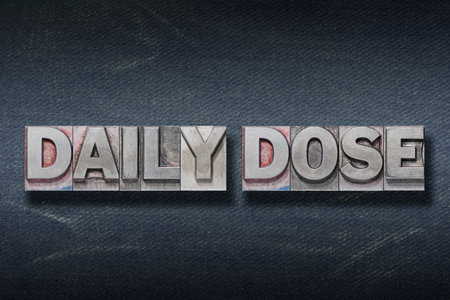 daily dose phrase made from metallic letterpress on dark jeans backgroundの写真素材