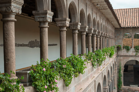 open second floor terrace with stone columns and fresh flowers of ancient Spanish buildingの写真素材