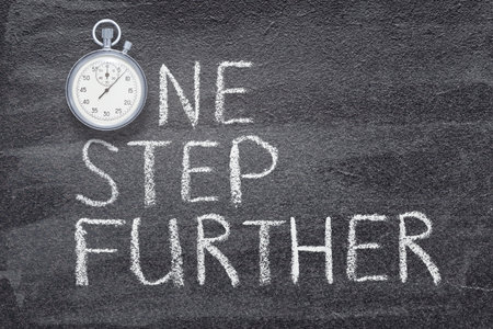 one step further phrase written on chalkboard with vintage precise stopwatchの写真素材