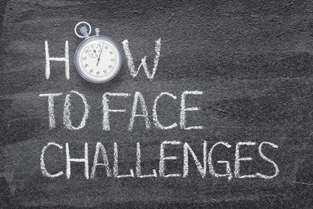 how to face challenges phrase written on chalkboard with vintage precise stopwatchの写真素材