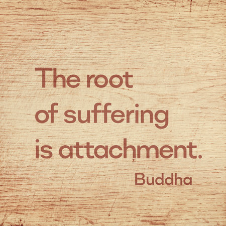 The root of suffering is attachment - famous quote of Gautama Buddha printed on grunge wooden boardの写真素材