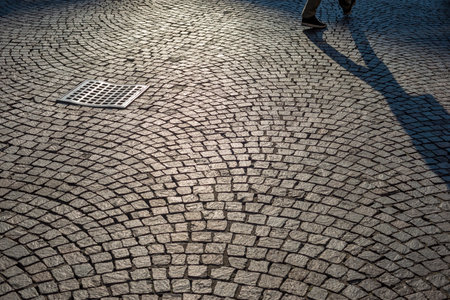 scenic cobblestone pavement by sunny morning in Milan with pedestrian shadowの写真素材