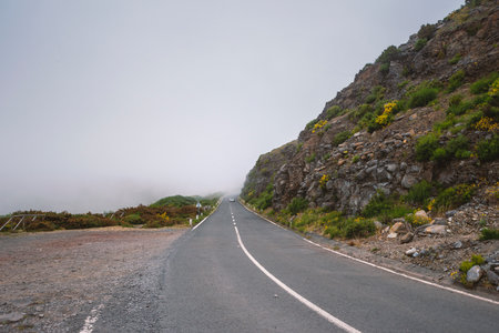 foggy mountain road with distant car on Madeira Island, Portugalの写真素材