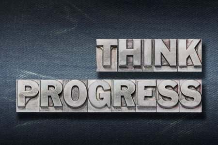 think progress phrase made from metallic letterpress on dark jeans background