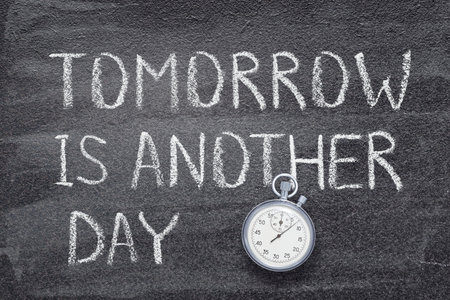 tomorrow is another day phrase written on chalkboard with vintage precise stopwatchの写真素材