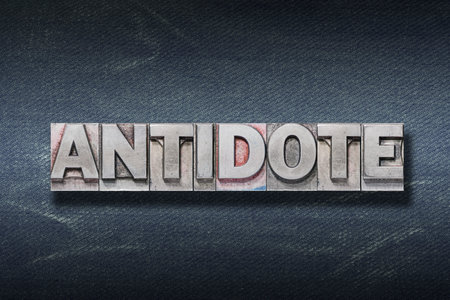 antidote word made from metallic letterpress on dark jeans backgroundの写真素材