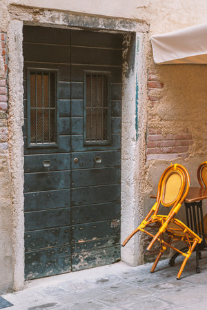 closed entrance wooden door with vintage chair in Venice, Italyの写真素材