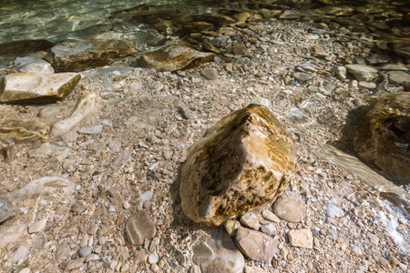 big stone surrounded by crystal clear mountain river watersの写真素材