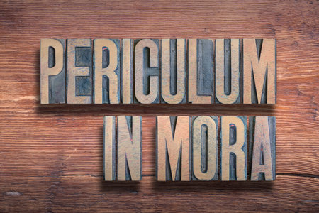 Periculum in mora ancient Latin phrase meaning There is danger in delay , combined on vintage varnished wooden surfaceの写真素材