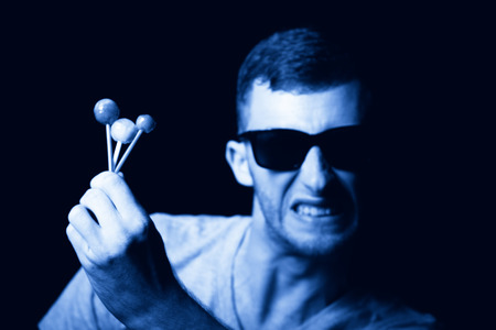Agressive young man with lollipops in handの写真素材