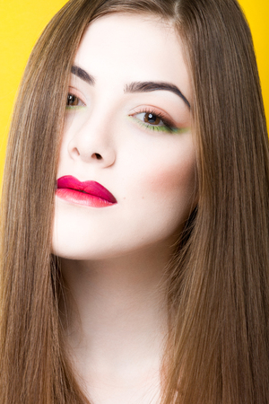 Close up beauty portrait of young white girl with creative makeup and hair isolated on yellow background.の写真素材