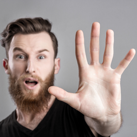 Shocked and worried young man isolated on gray backround. Emotional portraitの写真素材
