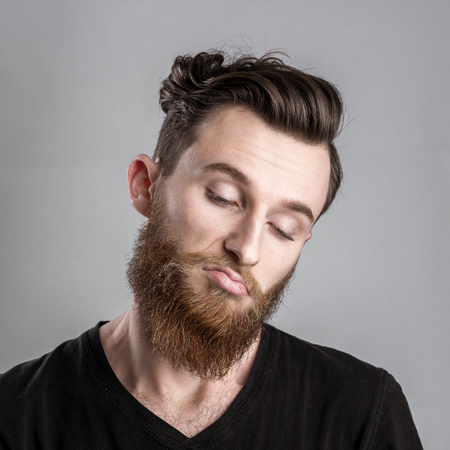 Moody and sad young man isolated on gray backround. Emotional portraitの写真素材