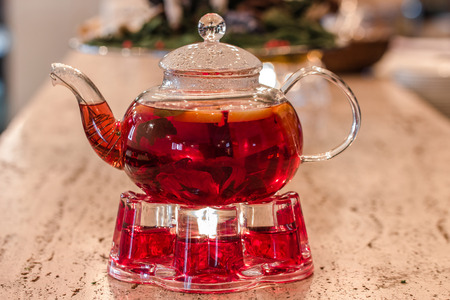 Glass teapot with red fruit tea on a standの写真素材