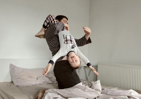 Father and son fun on the bedの写真素材