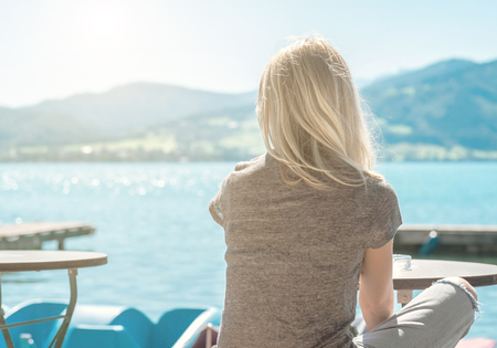 Woman recreation on pier, at summer sunny day, on lake with mountains view. Happy summer vacation in European destination.の写真素材