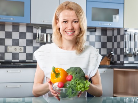 Woman holding  fresh vegetables in hands at  the kitchenの写真素材