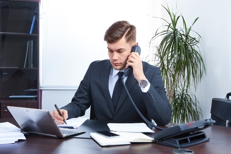 young businessman working in the Office and talking on the phoneの写真素材