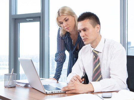 Business people working together on laptop in office at deskの写真素材