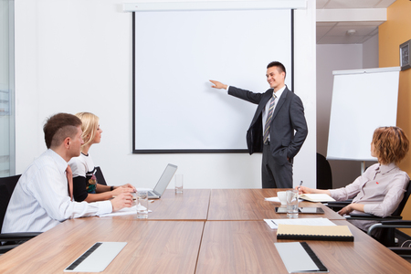 Manager presenting whiteboard to his colleagues in the officeの写真素材