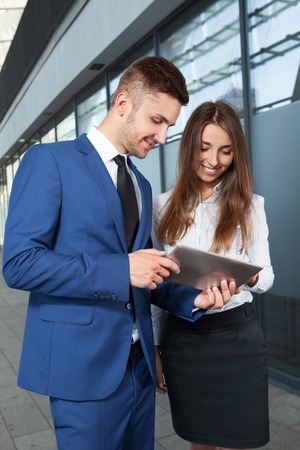 Business people or businessman and businesswoman working outdoor, using pad or tablet computerの写真素材