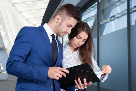 Business people or businessman and businesswoman working outdoor, using pad or tablet computerの写真素材