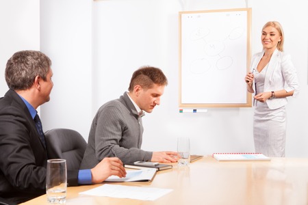 Giving presentation young executive during meeting woman pointing flip chartの写真素材